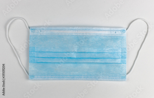 Single new protective blue medical face masks on white background. The concept of safety and prevention during an epidemic of viral infection COVID-19. Top view