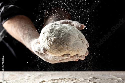 White flour flying into air as pastry chef in white suit slams ball dough on white powder covered table. concept of nature  Italy  food  diet and bio