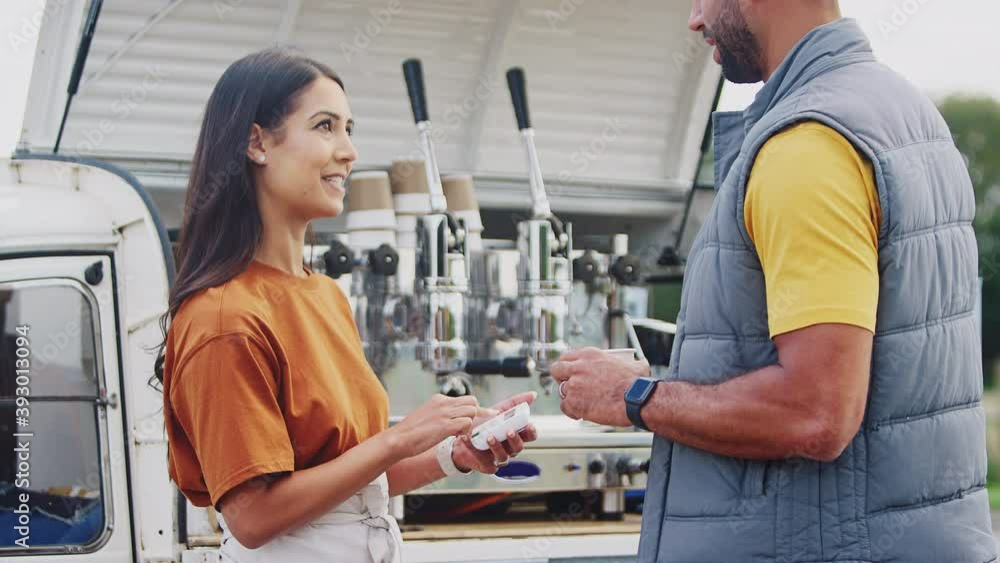 Male customer making contactless payment to female owner of mobile coffee van using credit or debit card - shot in slow motion Male customer making contactless payment to female owner of mobile coffee van using credit or debit card - shot in slow motion