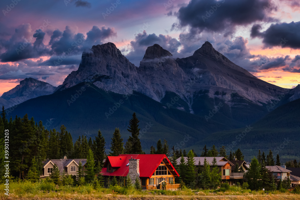 Obraz premium Beautiful view of Residential Homes with Canadian Rocky Mountains in the background. Colorful Dramatic Sunset. Taken in Canmore, Alberta, Canada.