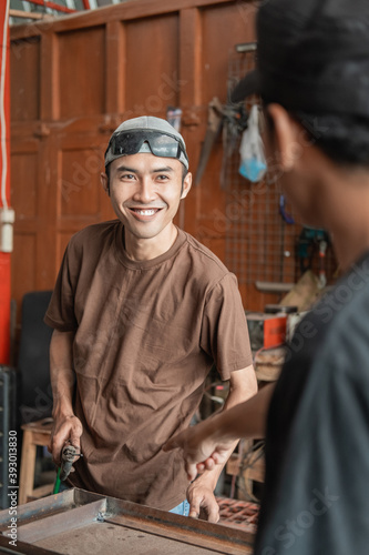 male welder smiles when asked to work according to the orders of the workshop business owner in the welding workshop garage