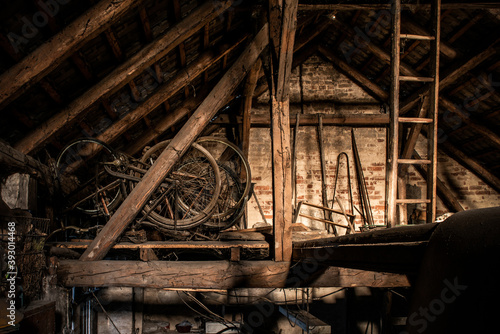 A rusty old vintage bikes in a barn with old farm machinery