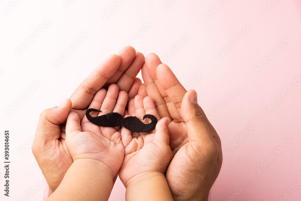 Obraz premium Father and his son kid uses hand holding black mustache, studio shot isolated on white background, Prostate cancer awareness month, Fathers day, minimal November moustache concept