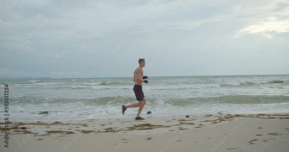 the sportsman worms up before start to train, he runs on the beach early morning the sportsman worms up before start to train, he runs on the beach early morning