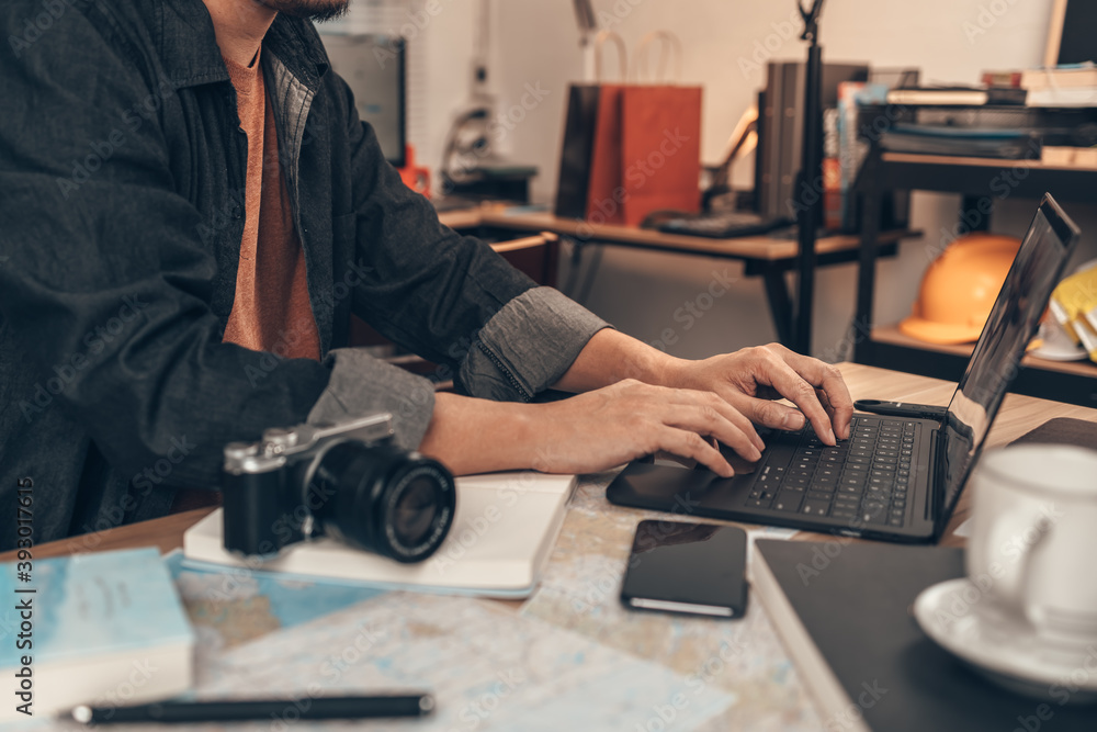 Tourist use laptop for search location and planing travel. Map, Coffee, Toast, Camera, Book, and Pen on the table. Tourist planning vacation-holiday with map. Tourist use laptop for search location and planing travel. Map, Coffee, Toast, Camera, Book, and Pen on the table. Tourist planning vacation-holiday with map.