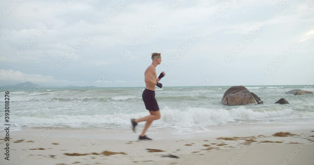 Young strong runner exercising on the beach, the warm up before start boxing Young strong runner exercising on the beach, the warm up before start boxing