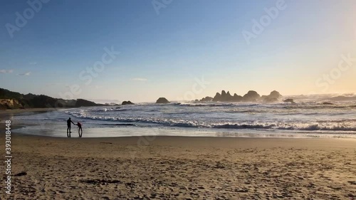 Mother and child running from waves silhouette at sunset