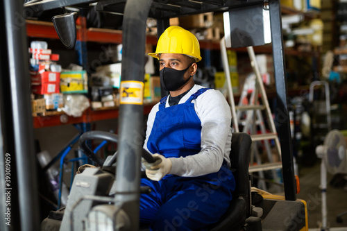 Foreman drives forklift in protective mask at the warehouse of a hardware store