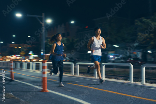 Asian couple jogging in the city streets at night.