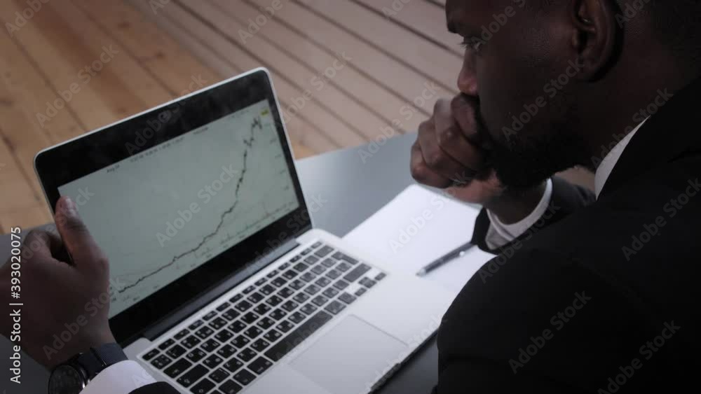 Black Businessman using laptop for analyzing data stock market, forex trading graph, stock exchange trading online, financial investment concept. close up Black Businessman using laptop for analyzing data stock market, forex trading graph, stock exchange trading online, financial investment concept. close up