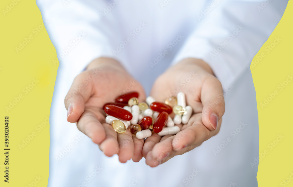 Many pills and vitamins in the hands of doctor. Isolate on yellow background Many pills and vitamins in the hands of doctor. Isolate on yellow background