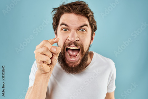 Man with disgruntled facial expression gesturing with hands studio lifestyle blue background photo