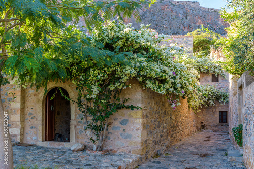 Traditional architecture with  narrow  stone street and a colorfull bougainvillea in  the medieval  castle of Monemvasia  Lakonia  Peloponnese  Greece.