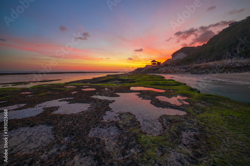 Seascape. Beach with rocks and stones. Low tide. Pink sunset. Slow shutter speed. Soft focus. Melasti beach, Bali, Indonesia