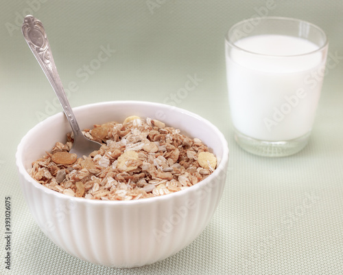 Homemade cooked oatmeal cereals with ceramic mug, metal spoon and glass of milk on blue background retro style