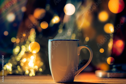 Mug with tea or mulled wine on christmas background with bokeh