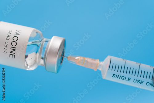 Vaccine vial with syringe isolated over blue background. Medical concept shows a medical vial and coronavirus vaccines coronavirus