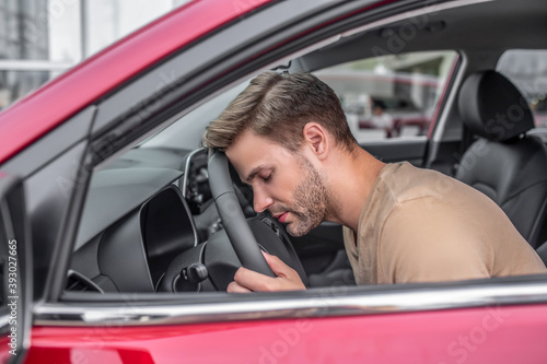 Tired young male resting his head on steering wheel © zinkevych