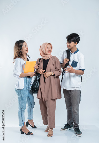 Portrait of conversation college friends carrying a bag and book on an isolated white