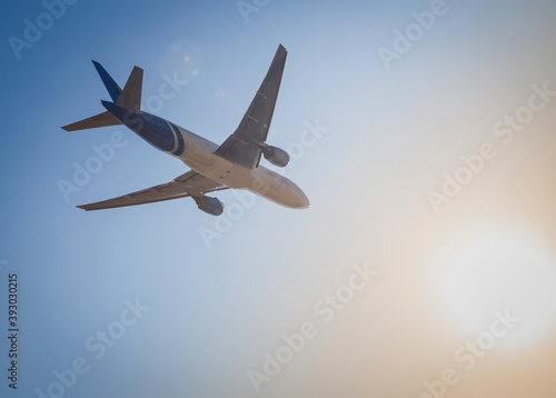 White plane flies in the sky. Bottom view. Takeoff and landing. Arrival and departure. Passenger plane isolated on blue background. Airplane flying. Travel by air transport. Copy space.