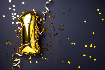 Gold foil balloon number and digit, one 1. Birthday greeting card. Anniversary celebration event. Banner. Copy space. Stylish golden numeral, light bokeh, glitter, black background. Numerical digit