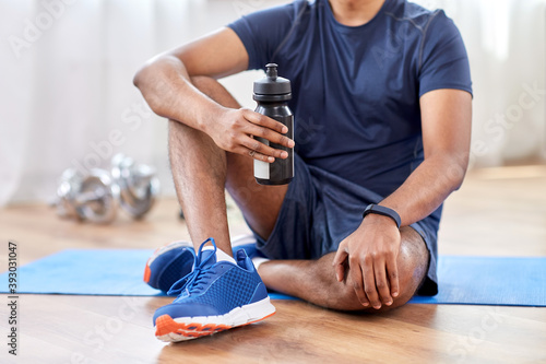 Fototapeta Naklejka Na Ścianę i Meble -  fitness, sport and healthy lifestyle concept - smiling indian man drinking water after training at home