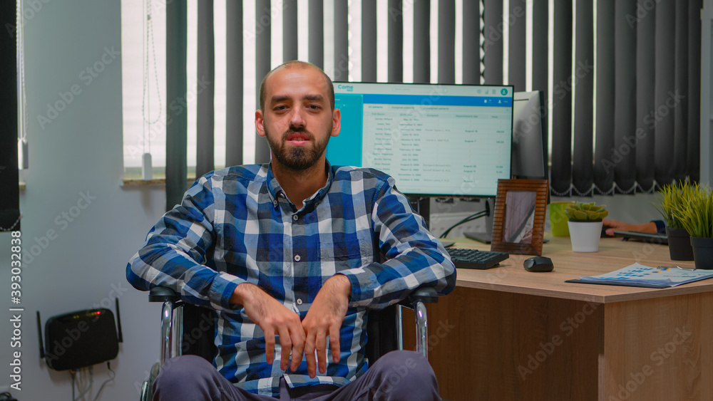 Φωτογραφία Handicapped disabled businessman in wheelchair waving at videocall having online conference in business office