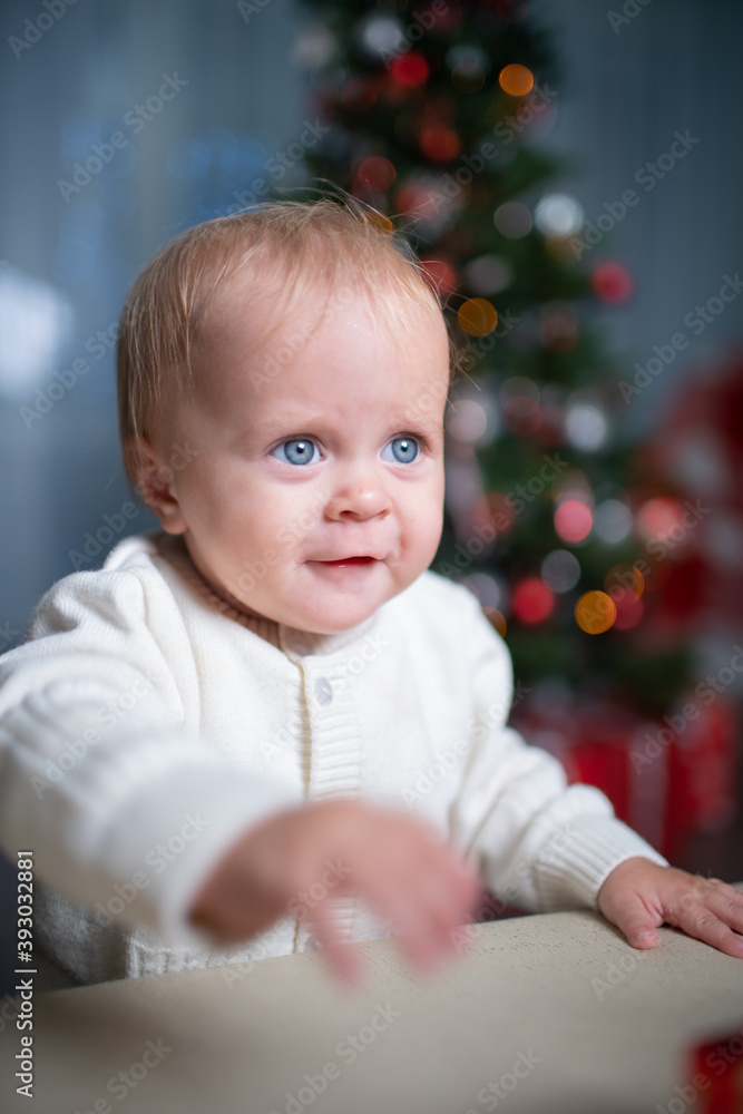 A baby toddler near a Christmas tree A baby toddler near a Christmas tree