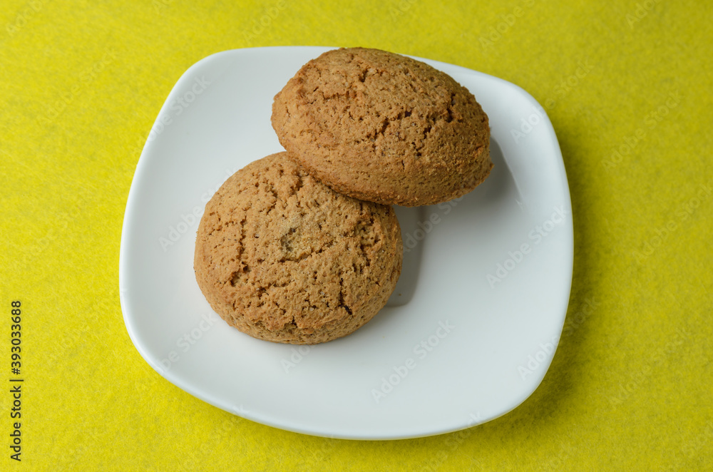 Oatmeal cookies in a white plate on a blurry yellow background. Oatmeal cookies in a white plate on a blurry yellow background.