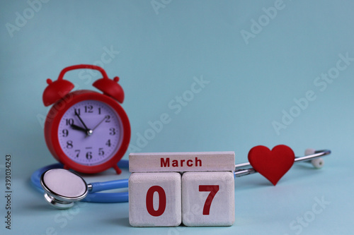 7st March. White wooden calendar blocks with date, clock and stethoscope on a blue pastel background. Selective focus. health concept photo