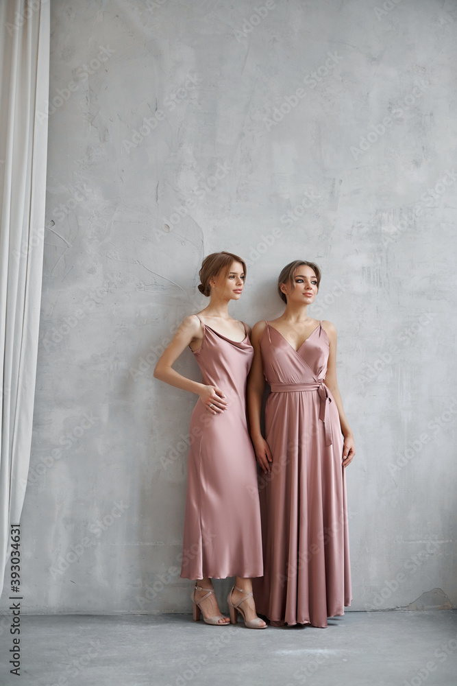 Two Beautiful sexy women in a light beige silk dress. Noise, out of focus
