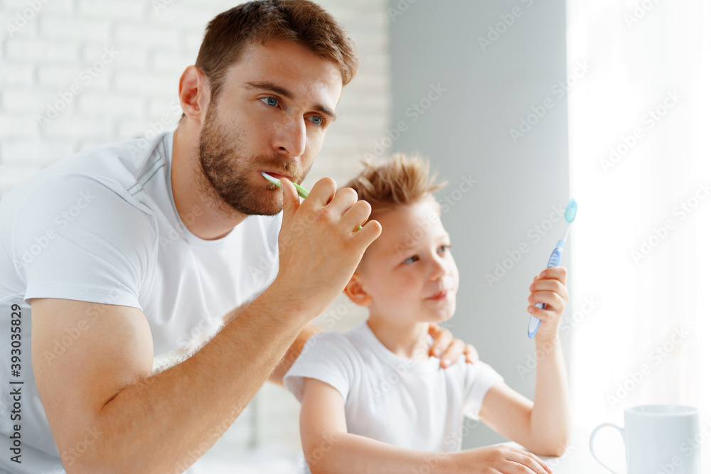 Dad and little son brushing teeth together Dad and little son brushing teeth together