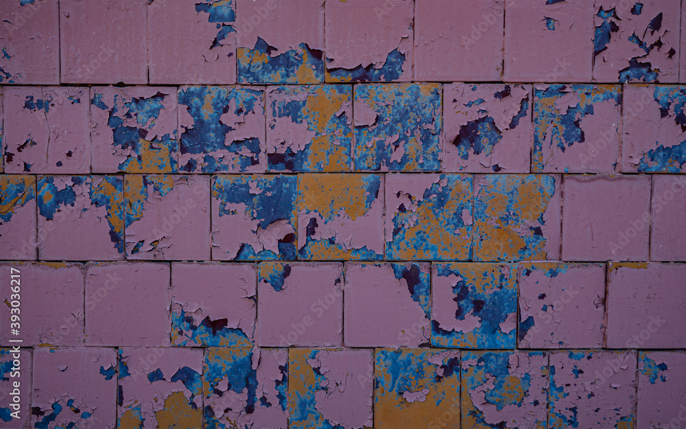 Paint peels off on a rough background. Broken tile, peeling paint multicolor, avant-garde walling of an old house, broken mosaic, abstract background