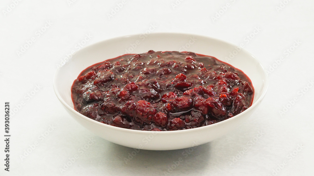 Fresh cooked homemade delicious cranberry sauce close up in a bowl on kitchen table Fresh cooked homemade delicious cranberry sauce close up in a bowl on kitchen table