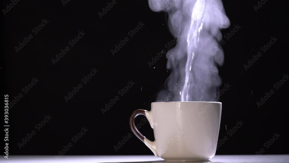 Slow motion of pouring hot water into a white porcelain coffee cup on a black background Slow motion of pouring hot water into a white porcelain coffee cup on a black background
