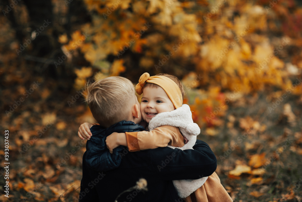 Cute funny smiling little girl and boy are hugging in autumn park. Happy cheerful kids. Cute funny smiling little girl and boy are hugging in autumn park. Happy cheerful kids.