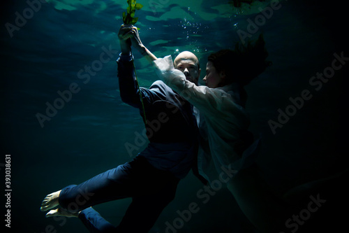 Young businessman dancing with his woman, symbolizing success, win, underwater. Emotional happy couple in pond. Concept romantic date and commitment to development of relations. Copy space