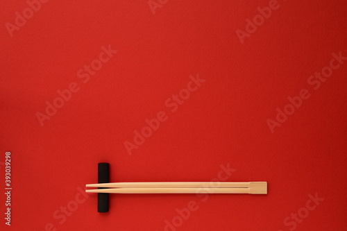 Disposable bamboo chopsticks on red background. 