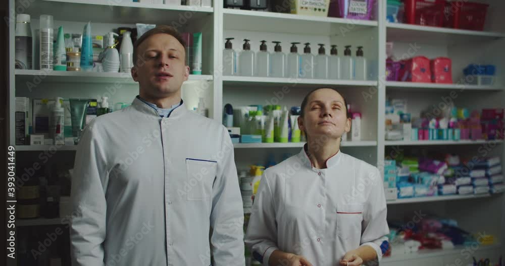 Two pharmacies man and woman are in masks at the pharmacy, protection from the virus. Pharmaceuticals take off their masks and breathe fresh air. High quality 4k footage Two pharmacies man and woman are in masks at the pharmacy, protection from the virus. Pharmaceuticals take off their masks and breathe fresh air. High quality 4k footage