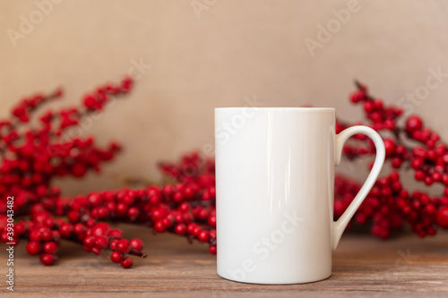 Mockup - White cup on Christmas holly berry background. Coffee or tea mug