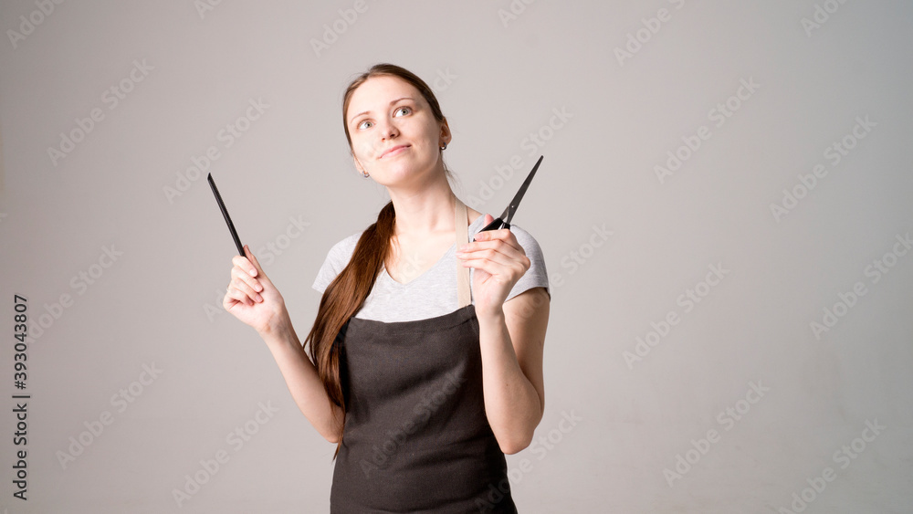 Young beautiful female hairdresser holding  hair clipper