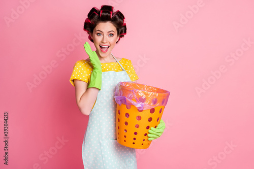 Portrait of nice attractive cheerful cheery glad brown-haired maid holding in hands trash basket isolated over pink pastel color background