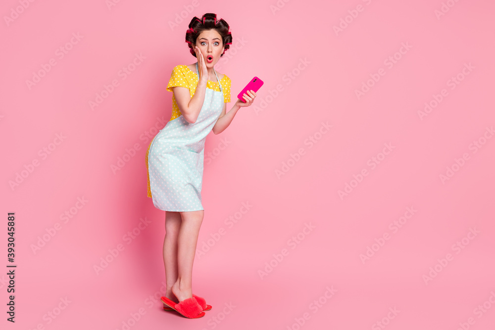 Full length body size view of pretty amazed housemaid using gadget browsing news reaction blogging posing isolated on pink color background Full length body size view of pretty amazed housemaid using gadget browsing news reaction blogging posing isolated on pink color background