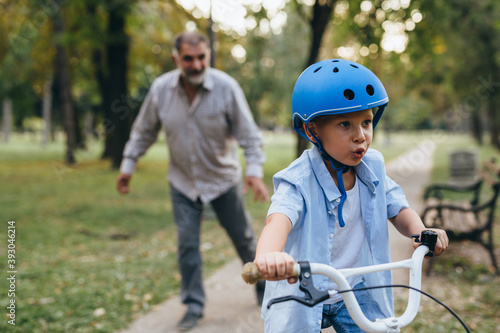 boy teaching to ride bike with his grandfather in public park