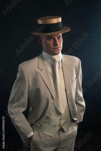 Man wearing boater hat and suit standing inside.