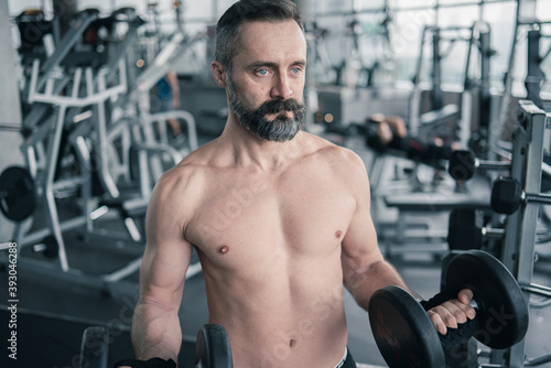 Training in gym, Handsome man with a mustache, do muscle building exercises using dumbbells, focusing on lifting and sit-ups in a fitness sport