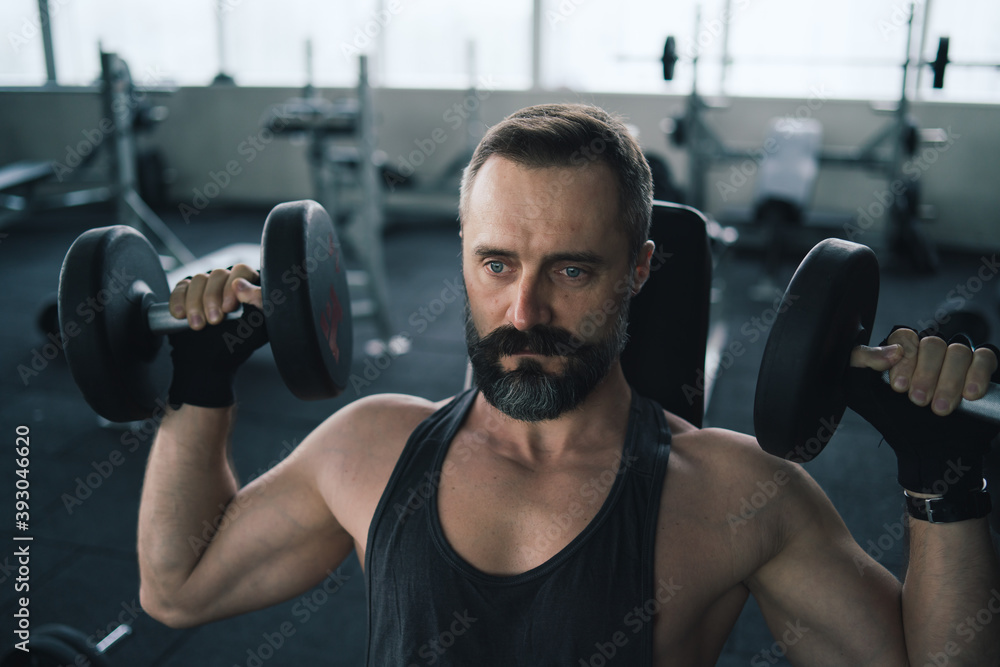 Training in gym, Handsome man with a mustache, do muscle building exercises using dumbbells, focusing on lifting and sit-ups in a fitness sport Training in gym, Handsome man with a mustache, do muscle building exercises using dumbbells, focusing on lifting and sit-ups in a fitness sport