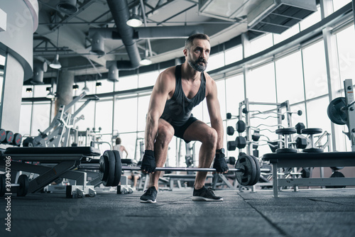 Training in gym, Handsome man with a mustache, do muscle building exercises using dumbbells, focusing on lifting and sit-ups in a fitness sport.