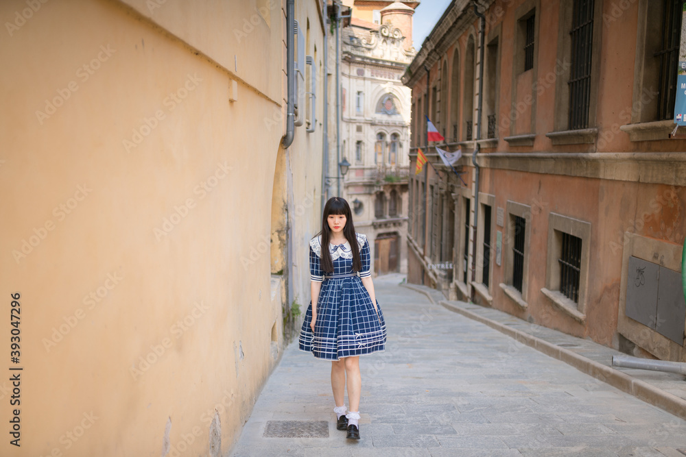 Asian women in retro blue long dress walking in the street of an old French town,Chinese girl traveling in Europe