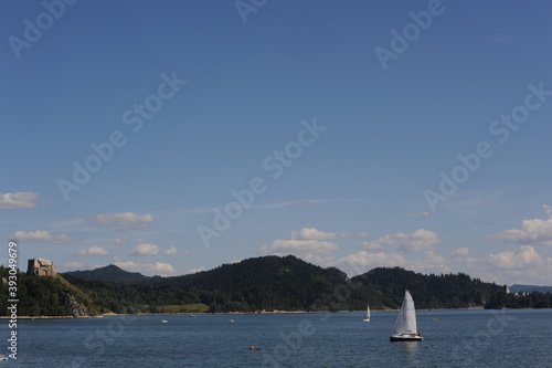 Fototapeta Naklejka Na Ścianę i Meble -  Blue waters of Czorsztyn dam lake with yacht and green hills and mountains and blue sky with clouds in summer in southern Poland